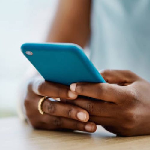 African woman using a cellphone in an office alone